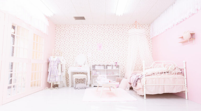 ピンクの花柄壁紙の女の子部屋。天蓋付きベッドと白いドレッサー